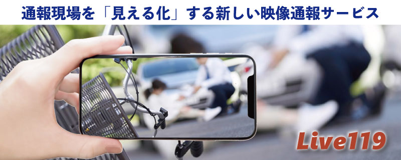 通報現場を「見える化」する新しい映像通報サービス Live119(片手に持ったスマートフォンの画面に、交通事故の現場で倒れている人や自転車、救護しているタクシー運転手が映し出されている写真)