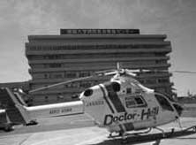 ドクターヘリが、病院の建物らしき大きな建物の前にあるヘリポートに停車している白黒写真
