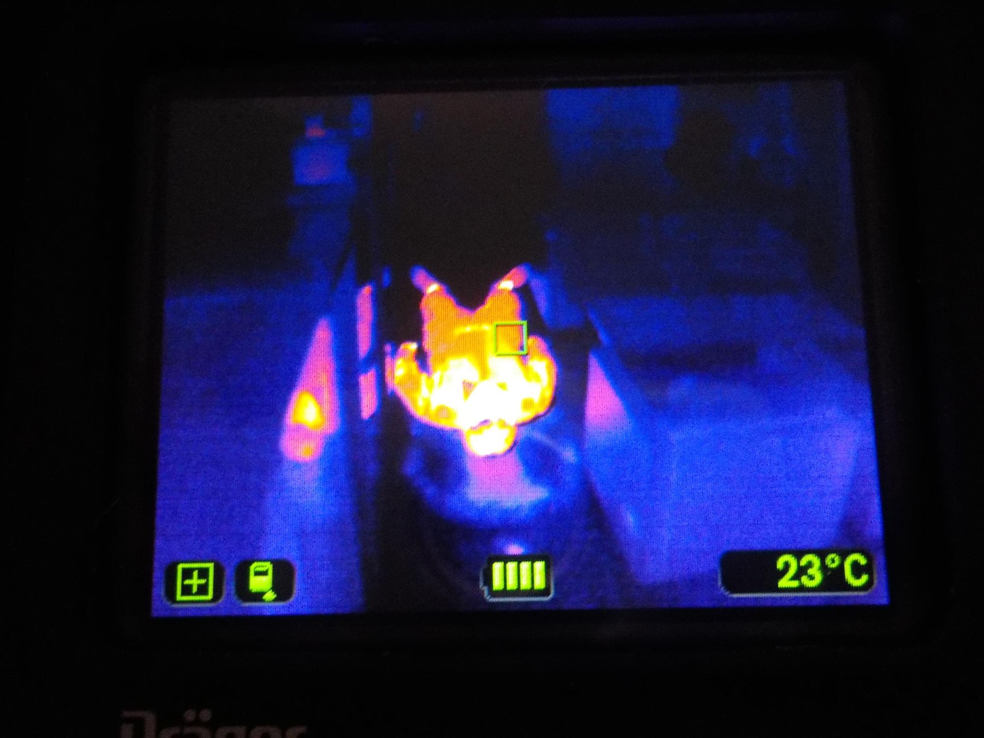 暗闇の中で熱画像を捉えた画面が表示され、画面中央に明るい黄色やオレンジ色で高温の物体が写り、画面下にはバッテリー残量や室温23°Cなどの情報が表示されている写真