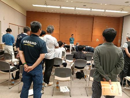 建設事業者である相輪会の従業員が三角巾の取り扱い説明を真剣に聞いている画像
