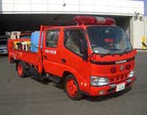 小型トラックをベースとした赤い車体で、平ボディの荷台には青いポリタンクのような水槽と小型ポンプが積載されている資機材搬送車を斜め正面より撮影した写真