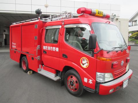 赤い車体に白文字で秦野市消防署と書かれたシャッター式の収納庫や丸目と角目のライトを備えたコンパクトな消防車を斜め正面より撮影した写真