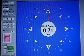 青い背景に白い文字で風速を示す「Wind Speed 0.71 m/s」と方位盤が表示された、消防車両の指揮用モニターに映し出された風向風速計やGPSなどの災害現場情報を確認するための画面の写真