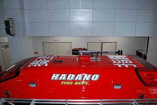 白色の大きな文字で「HADANO FIRE DEPT.」と書かれた消防車の赤い車両の屋根部分のクローズアップ写真