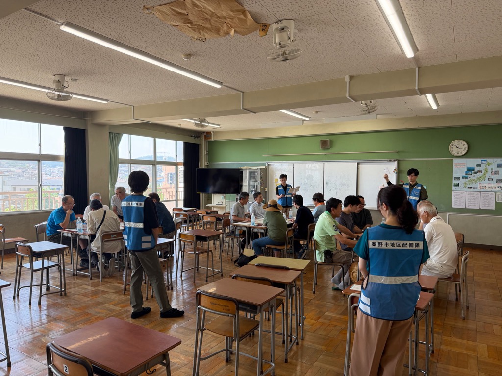 小学校の活動室で避難所運営訓練に参加する参加者の写真
