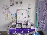 紫色の布で装飾されたテーブルに「話してもいいのかな 聞かせてほしいな」と書かれたDV防止啓発ポスターと多数のパンフレットが並び、紫のリボンとモールで彩られた女性支援相談窓口の展示写真