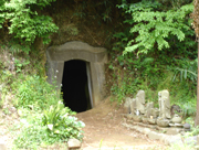 草木が生い茂る斜面に石で縁取られた洞窟の入り口があり、その手前に小さな石仏が並んでいる長福寺の五神窟の写真