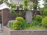 小学校の正門前の、手入れされた植栽の中央に設置された前田夕暮歌碑の写真