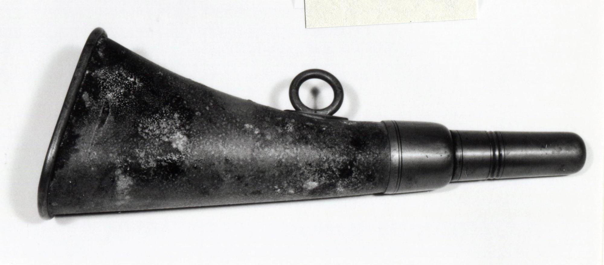 錆と経年劣化が見られる黒い金属製の筒状の熊よけラッパを、白い背景の上に置いて撮影した写真