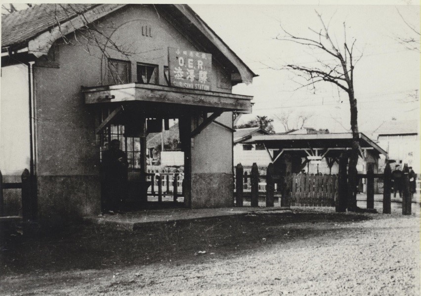 「渋沢駅」と駅名の看板が取り付けられた古い駅舎のモノクロ写真
