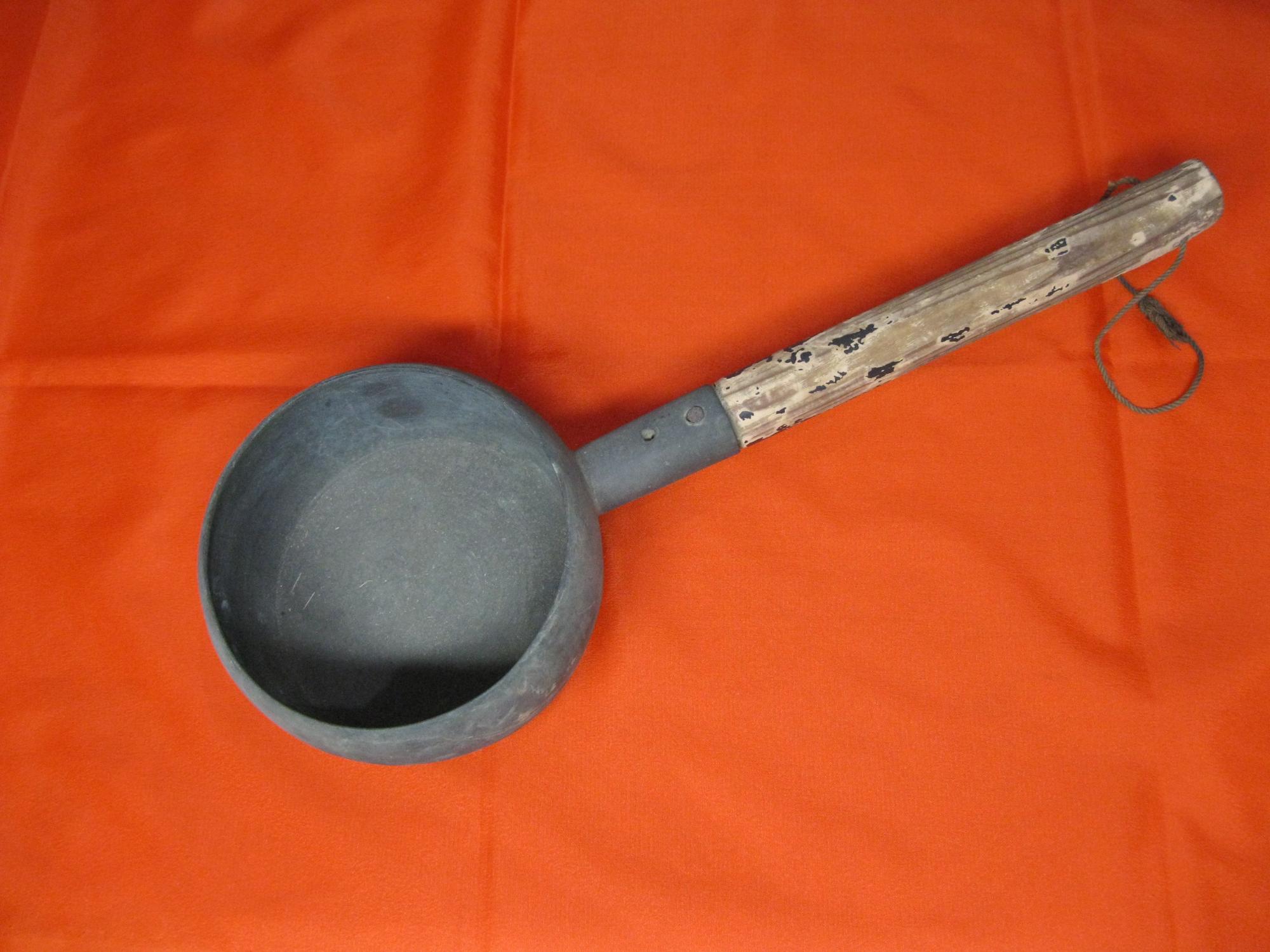 使い込まれた風合いの木の柄がついた、金属製の火のしを、背景に赤い布を敷いて真上から撮影した写真