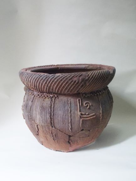 丸みを帯びた胴体に縄目模様が全面に施され、太く丸く張り出した口縁部には綿密な斜線文が刻まれ、一部に渦巻状の装飾が加えられた縄文土器の写真