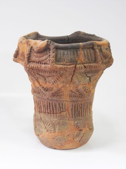 複数の破片を組み合わせて修復された、深鉢形で、表面に複数の文様が複雑に施されている土器の写真