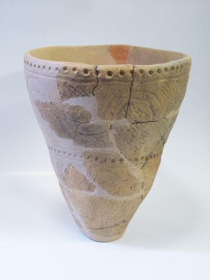 複数の破片をつなぎ合わせて修復された深鉢形で、表面や縁に点線の文様が施されている土器の写真