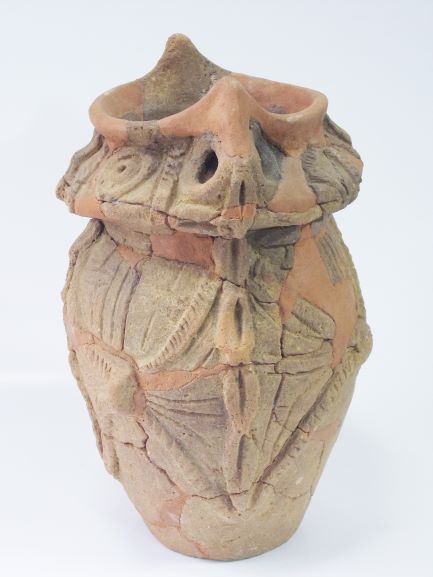 修復された深鉢形で、線や凹凸で模様が入った土器の写真