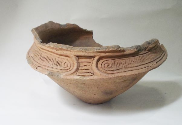 複数の文様が施された浅鉢形で、上部の口縁部分が欠損している土器の写真