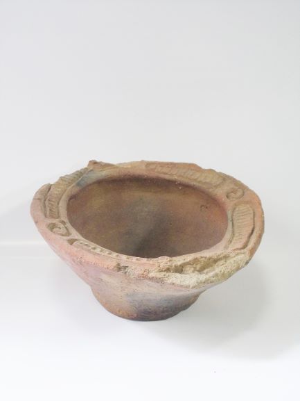 複数の文様が施された鉢形で、上部の口縁部分に渦巻き状の装飾がある土器の写真