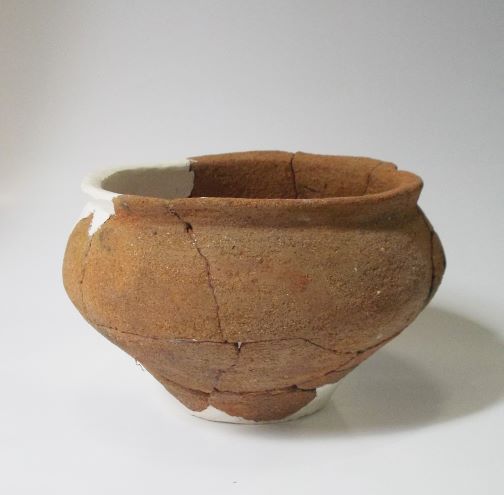 数か所が白い補修材でつなぎ合わされた、丸みを帯びた深鉢形で、表面には補修後のひびが見られる土器の写真