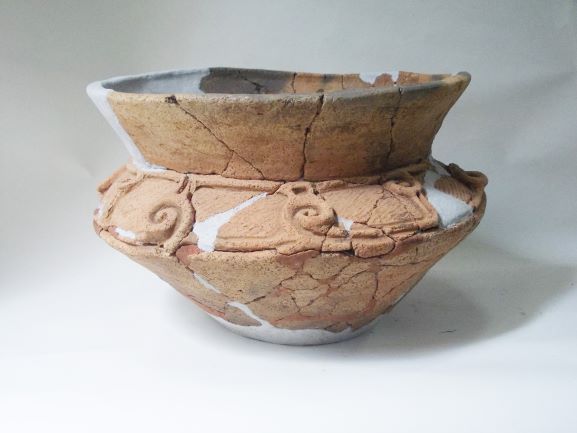 深鉢形で、表面には渦巻き状に隆起した装飾が施されている土器の写真