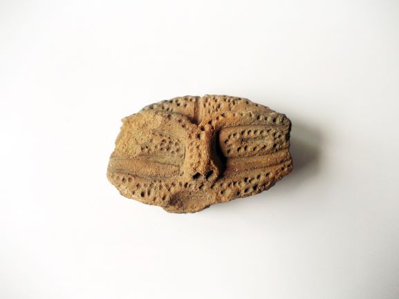 点線や直線で顔のような装飾がされた土器の破片の写真