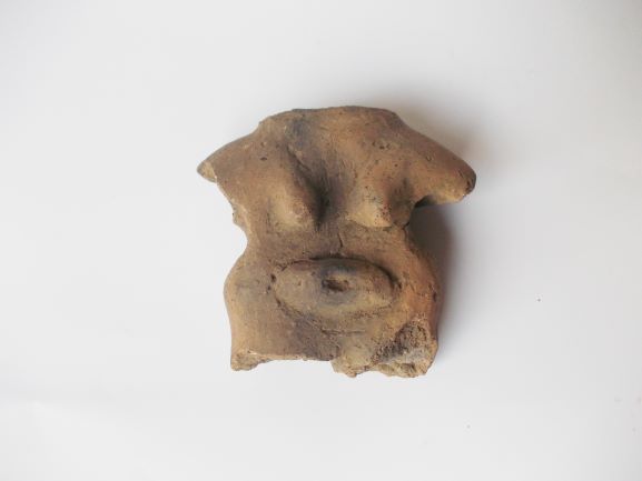 胸と下腹部が立体的に膨らみ、女性の胴体を模したような形の土器の破片の写真