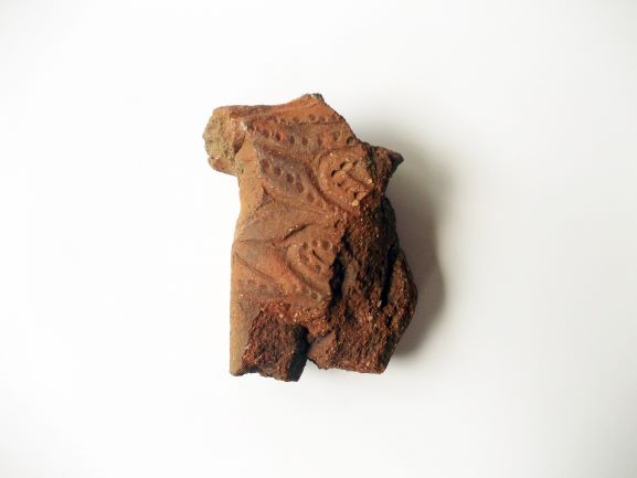 複数の点線や模様が刻まれた、赤茶色い土器の破片の写真