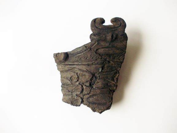 頭部に2つの突起がある鳥のような模様が描かれた深茶色の土器のかけらの写真