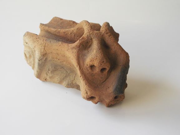 目や鼻、角のような形が立体的に作られた土器の破片の写真