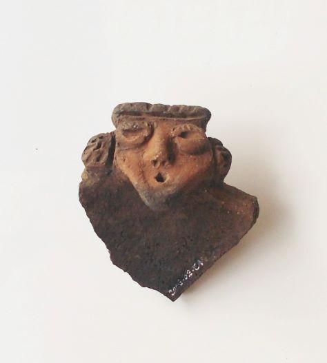 目、鼻、口、耳が立体的に表現された、人の顔をした土器のかけらの写真