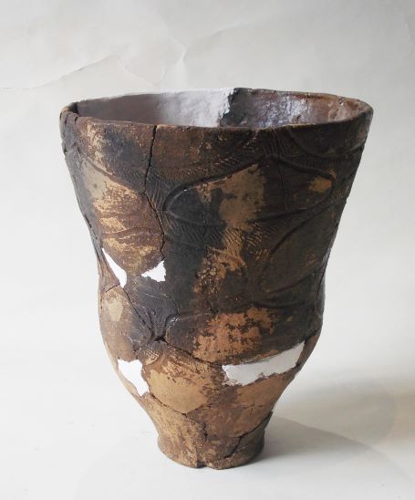 複数の破片を組み合わせて修復された深鉢形で、表面には複数の文様が施されている土器の写真