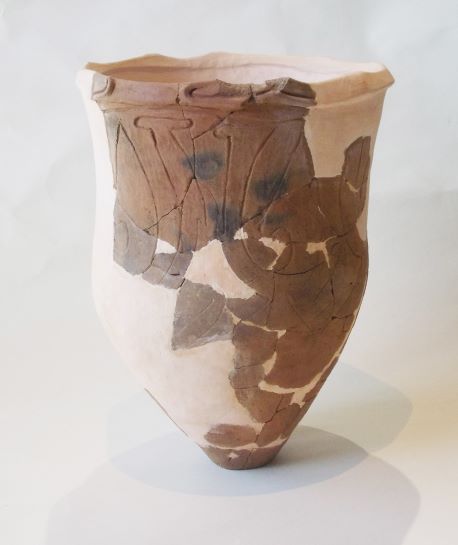 底部にかけて細くなった形状で、口縁部から胴部にかけて破損した破片が多数つぎ合わされ、もとの形に復元された深鉢形土器の写真