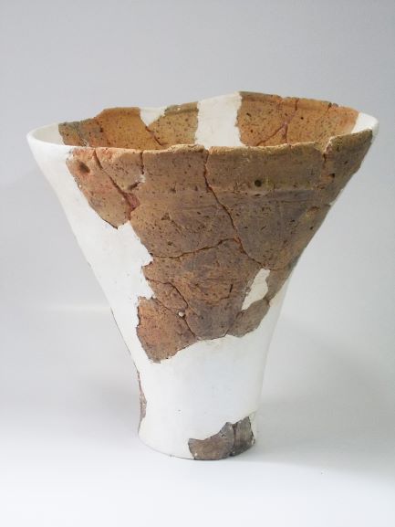 口縁部から底部にかけて逆円錐状に大きく広がり、多数の破片をつなぎ合わせて復元された、白い修復跡が目立つ深鉢形土器の写真