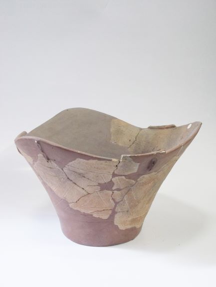 口縁部が波打った深鉢形で、茶色の修復材と破片で修復された土器の写真