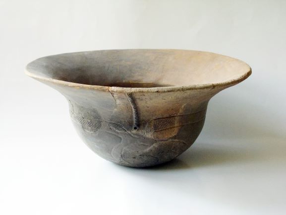 口縁部が大きく広がった浅鉢形で、胴体部分には線で文様が施された土器の写真