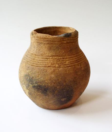 底部にかけて丸みを帯びた形状の壺で、胴体の中央部が黒く変色しており、口縁部には複数の横線が施されている土器の写真