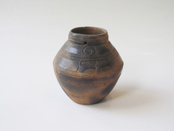 丸みを帯びた胴体を持つ壺で、口縁部から胴体にかけて複数の縄目文様と渦巻き文様が施され、全体的に黒く変色した土器の写真