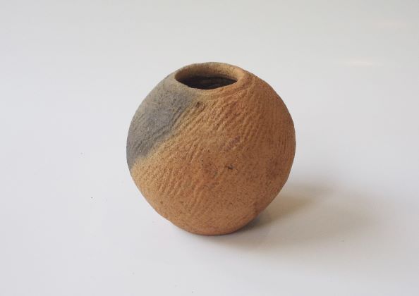 球体に近い形をした口が小さい壺形で、表面には全体的に斜めの線状の模様が施された土器の写真