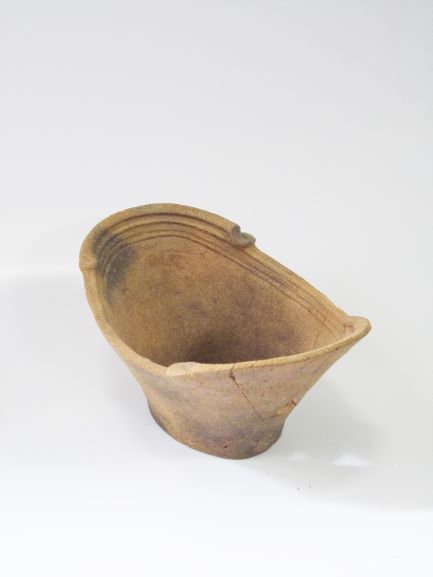 楕円形の舟形で、上部の縁に複数の線が刻まれ、左右が高く作られている土器の写真