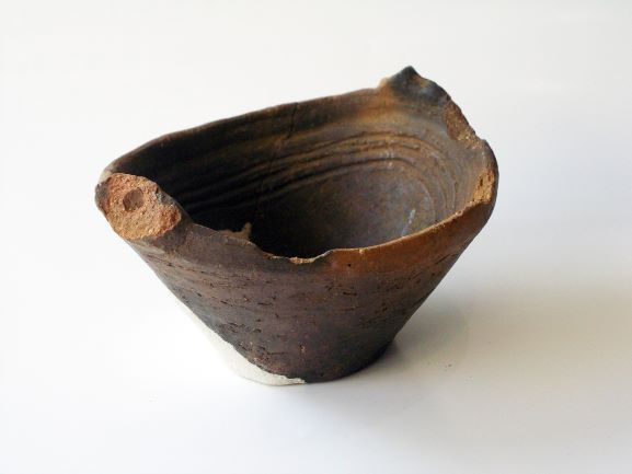 浅鉢形で内側に線状の模様が施され、口縁部に持ち手のようなものが見られる土器の写真