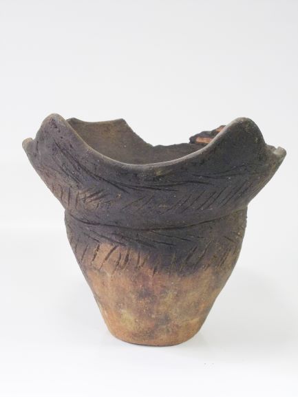 大きく波打つ口縁部と、その下に葉脈のような文様が施された深鉢形の土器の写真