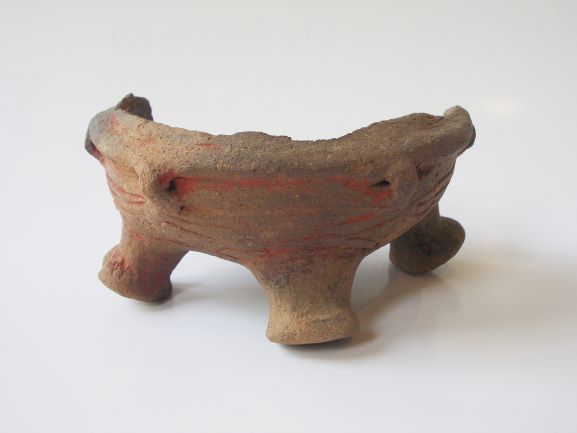 円錐形の三つの脚を持つ土器で、表面には横縞の線と赤い線が描かれており、口縁の一部が欠けている写真