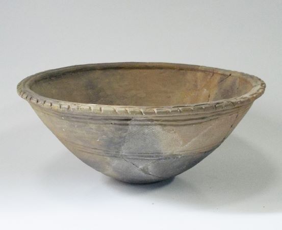 大きく広がった口と丸い底を持ち、口縁部には細かい文様、胴体には平行線が描かれた浅鉢形土器の写真