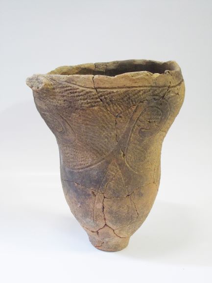 首部分がなだらかにくびれており、表面には線で複雑な文様が施された土器の写真