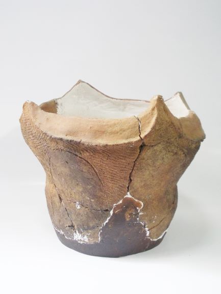 上部が山形に波打っており、表面には縄目模様が施された鉢形の土器の写真