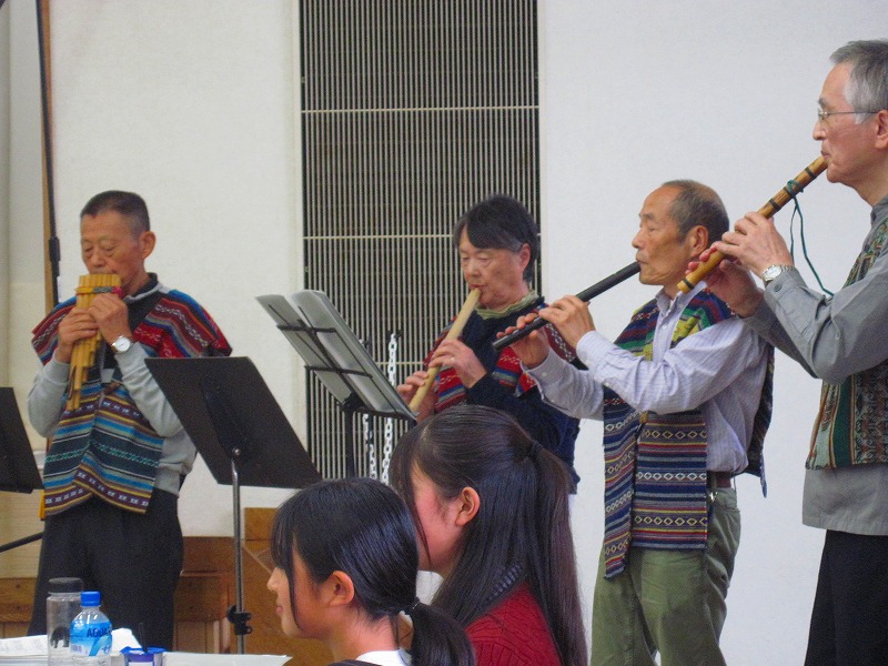 民族衣装のような色鮮やかなベストを着た人々が、様々な種類の楽器を演奏している写真