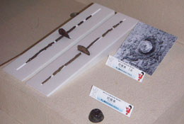 紡錘車と軸棒が白い布に置かれ、説明書きの札が添えられた紡錘車と写真が展示してある写真