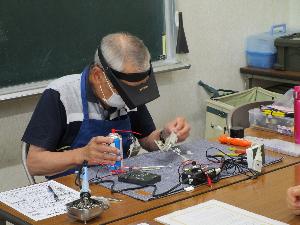 おもちゃの信号機を修理している様子。机上にはいろいろな修理機材が置かれている。