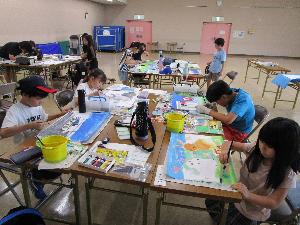 複数のテーブルそれぞれで、小学生数人が水彩画を描いている様子