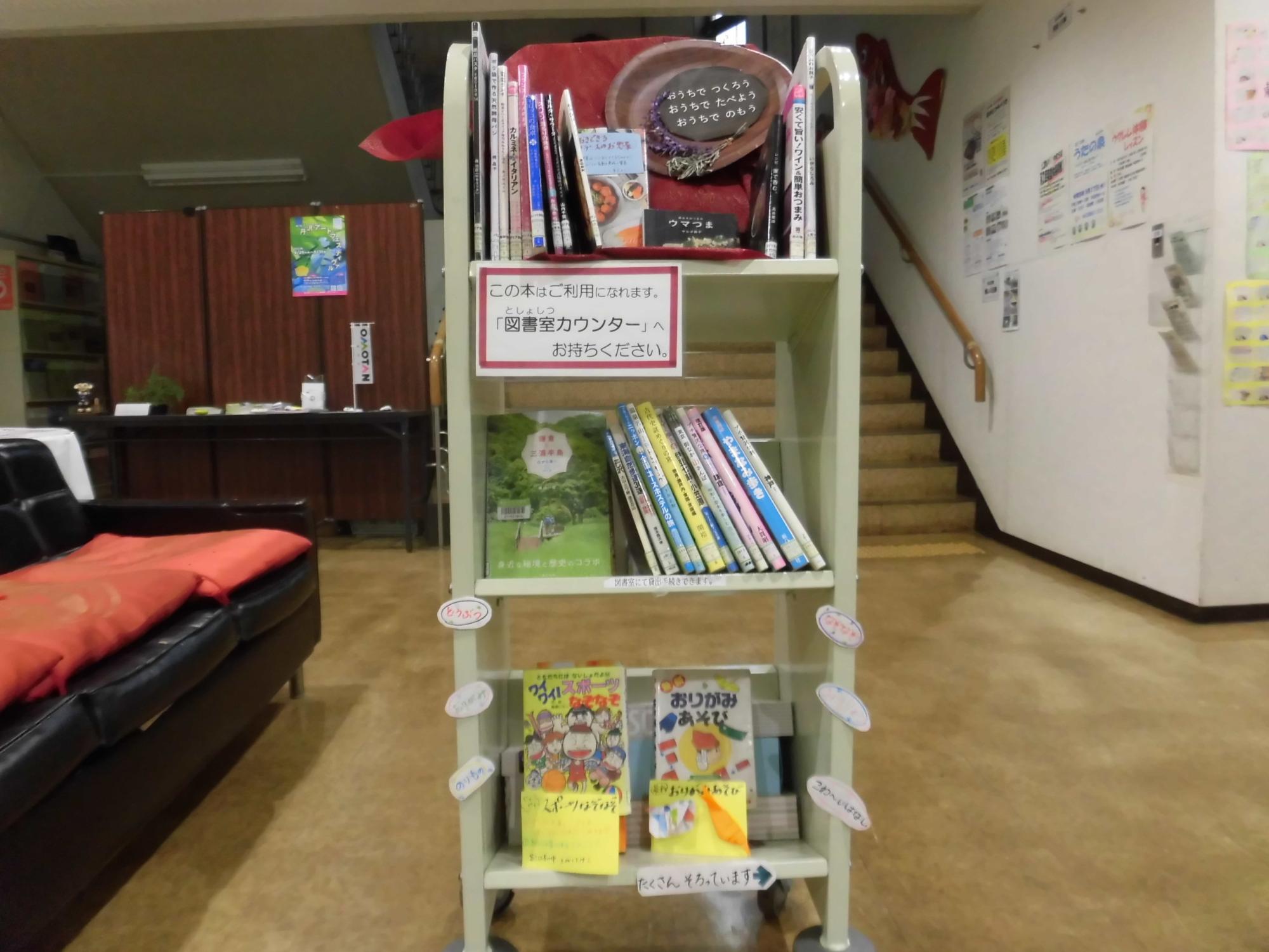 子供用の絵本が並べられた3段ワゴンに「この本はご利用になれます。図書室カウンターへお持ちください」と書かれたポップが貼られた写真