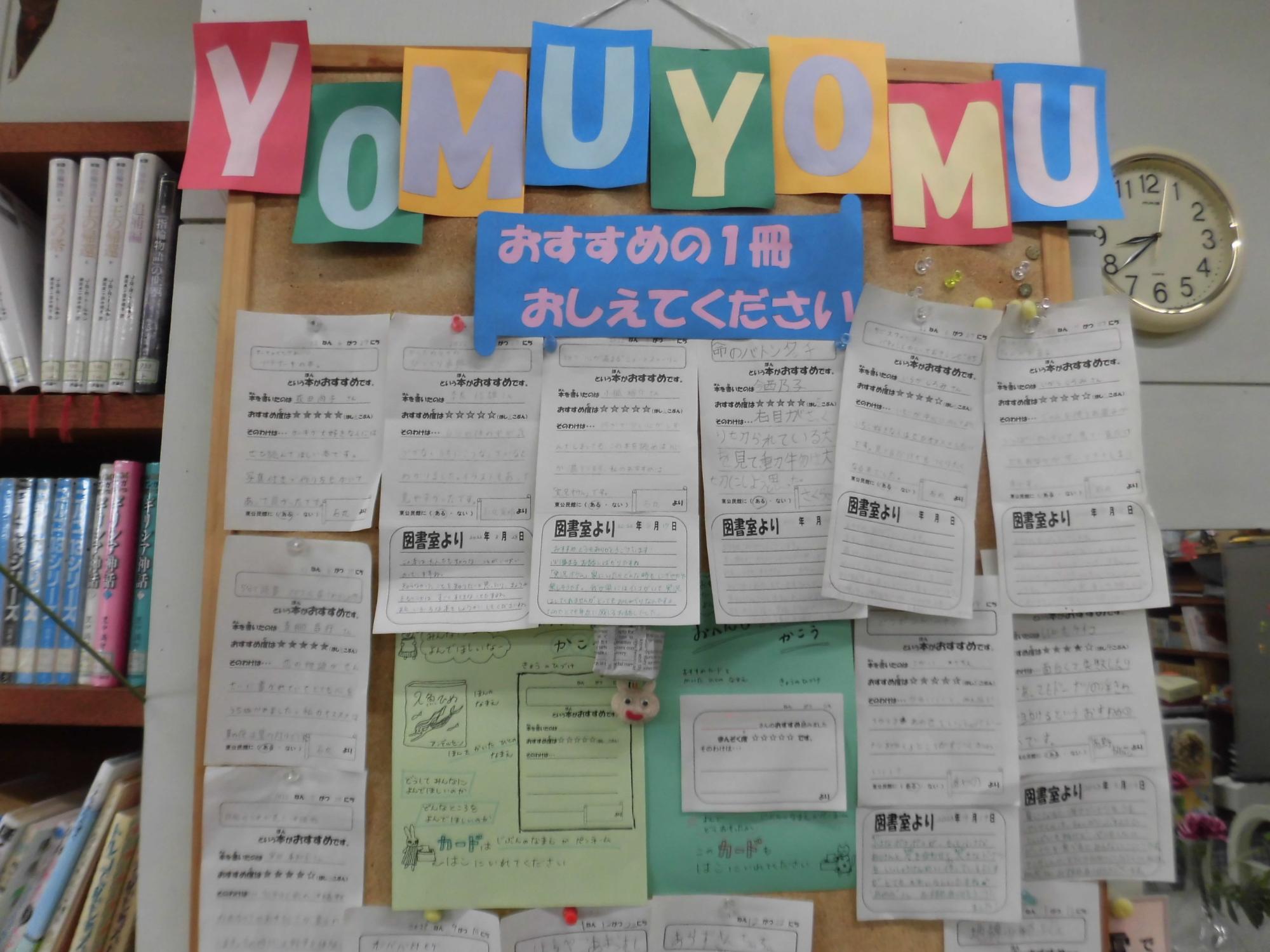 「YOMUYOMU」と書かれたカラフルな文字と、おすすめの本を紹介する手書きの紙が多数貼られている、図書室内の掲示板を近くで撮影した写真